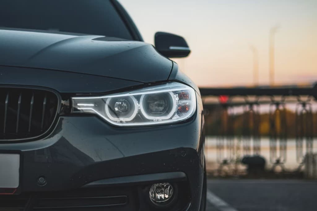 Dark luxury sedan with illuminated headlights at dusk