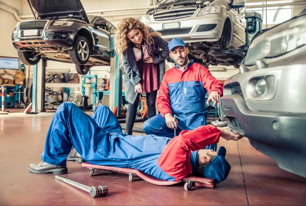 Mechanics inspecting the front of a silver vehicle in the workshop