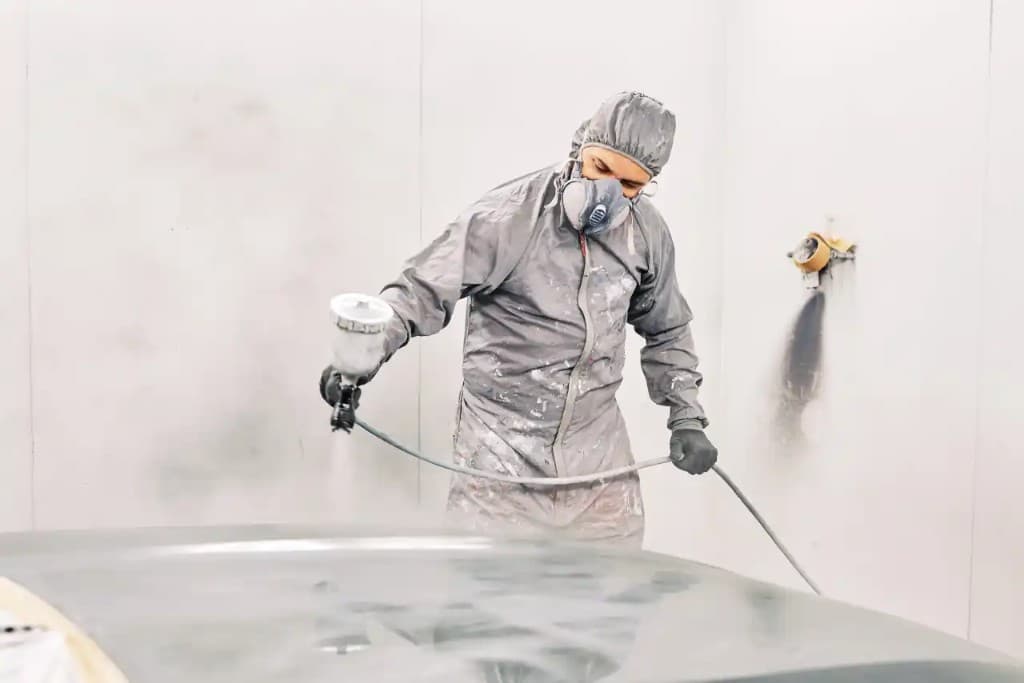 Technician in a spray booth painting a vehicle panel