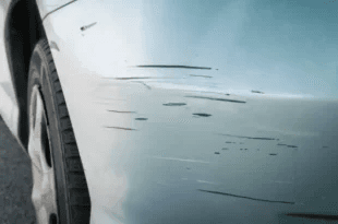 Close-up of dark scuffs and scratches on a light car bumper